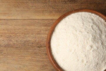 Coconut flour in bowl on wooden table, top view. Space for text