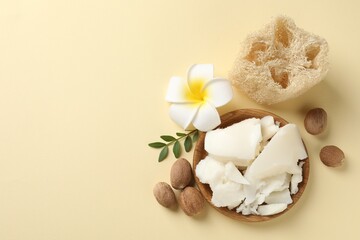 Natural shea butter, nuts, plumeria flower, leaf and loofah sponge on beige background, top view. Space for text