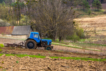 Blue Tractor Plowing Field in Rural Landscape