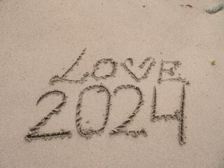 Fototapeta premium Sign love and 2024 on a sand of a beach.
