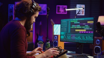 Music producer recording piano keyboard notes and editing them on a mixing console in his home studio. Skilled artist implementing advanced sound mixing techniques, equalization tools. Camera B.