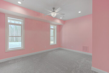 Empty Room With Pink Walls, Grey Carpet, Ceiling Fan, And Two Large Windows