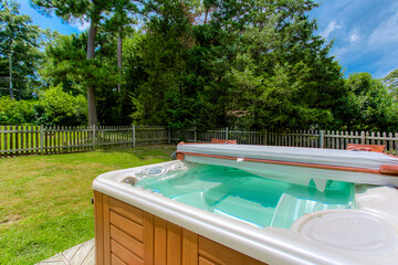 Outdoor Hot Tub In A Serene Backyard With Lush Trees And Wooden Fence
