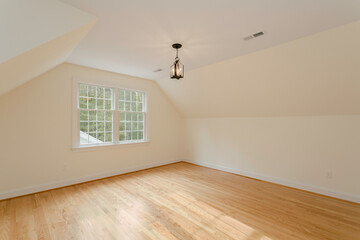 Sunlit Attic Room With Wooden Floors, Light Fixture, And Large Windows
