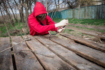 Person in Red Hoodie Using a Crowbar to Pry Up Wooden Boards Outside