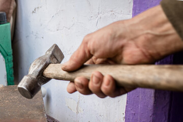 Close Up Of A Hand Holding A Hammer Above An Anvil