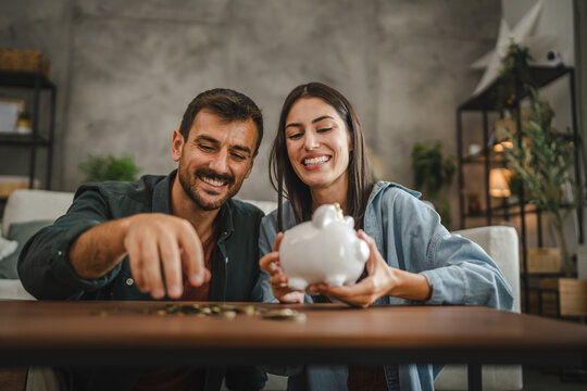 Adult couple save money coins in the piggy bank at home