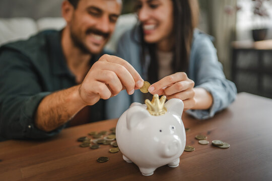 Adult couple save money coins in the piggy bank at home