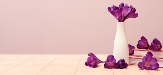 Vase with bouquet of beautiful crocus flowers and books on table. Banner for design