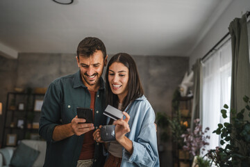 Portrait of couple buy online on mobile phone with credit card at home