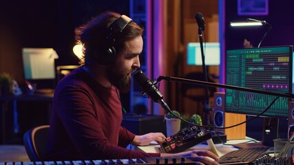 Music producer recording piano instrument and vocals to edit a new song, adjusting volume levels an...