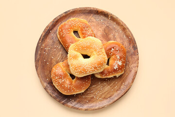 Plate of tasty bagels with sesame seeds on beige background
