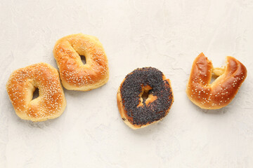 Tasty bagels with sesame and poppy seeds on light background