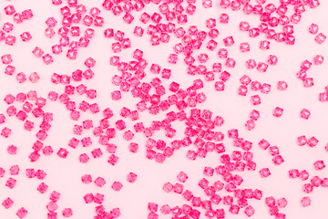 Texture made from acrylic beads scattered on a pink background.