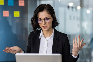 Businesswoman in office with confused expression during video call. Concept of workplace...