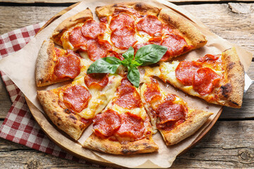 Tasty pepperoni pizza with basil on wooden table, above view