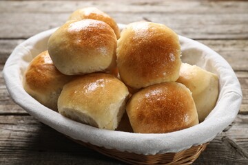 Delicious dough balls in basket on wooden table, closeup