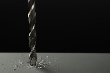 Drilling hole in grey surface on black background, closeup. Space for text