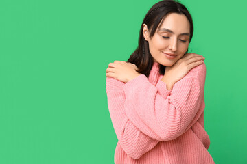 Obraz premium Young woman hugging herself on green background