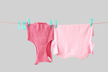 Bright clean clothes hanging on rope against grey background