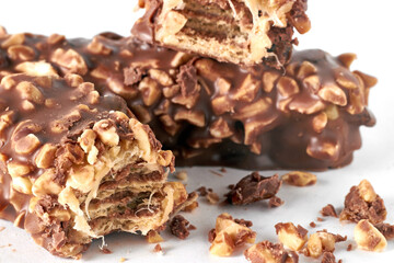 Wafer bar with nougat covered with nuts and chocolate on a white background. Internal section at a fracture with crumbs