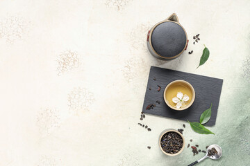 Teapot with cups, spoon of dry tea and leaves on white grunge background