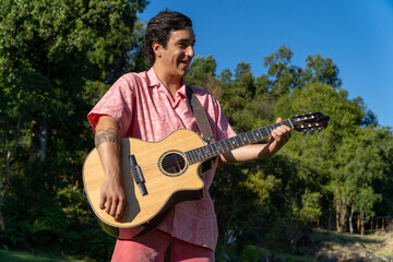 Man enjoying a sunny day, playing guitar in the home garden during summer.