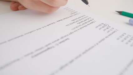 Obraz premium Female circles correct answers in standard math exam test paper with black pen. Student at desk filling up the answer sheet, choosing right answer.