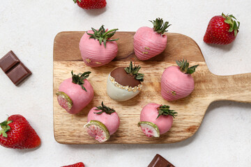 Wooden board with chocolate covered strawberries on white background