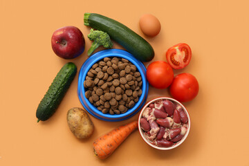 Bowl with dry pet food and vegetables on brown background