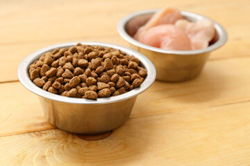 Bowls with meat and healthy dry pet food on wooden background