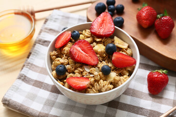 Bowl with tasty granola and berries on napkin, closeup