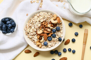 Napkin, nuts, bowl with raw oatmeal and berries on color background, closeup