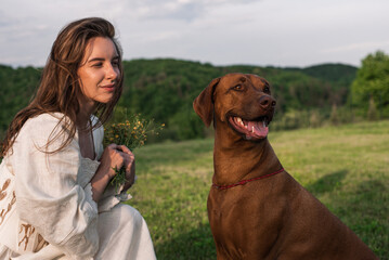 young beautiful female playing with her dog outside in the backyard with a gorgeous hill view