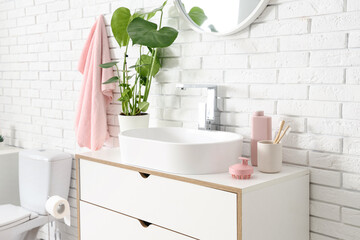 Interior of bathroom with hair scalp massagers on chest of drawers near sink