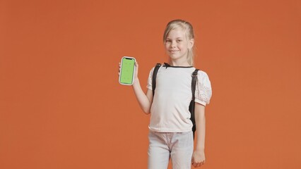 Young schoolgirl holds smartphone with green screen chroma key