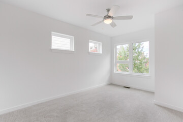 Fototapeta premium Minimalist White Room With Modern Ceiling Fan And Ample Natural Light