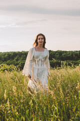 portrait of young attractive female outdoors in countryside meadow during golden sunset