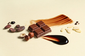 Composition with piece of tasty chocolate, cocoa beans and nuts on color background