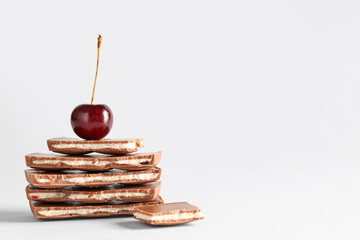 Composition with pieces of tasty chocolate and ripe cherry on light background