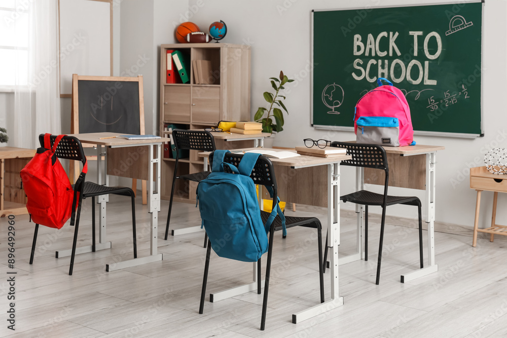 Sticker School desks, backpacks and blackboard in modern classroom