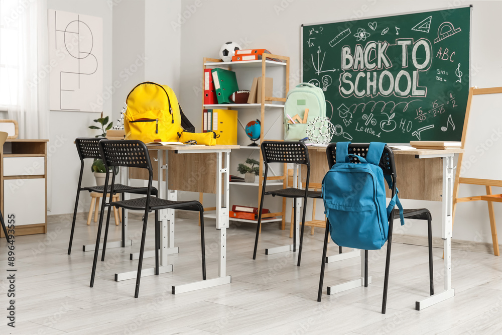 Sticker school desks, backpacks and blackboard in light classroom