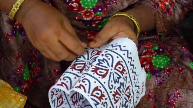 A woman sewing an Arabic Muslim head cap. An entrepreneur has made hats used for prayers.