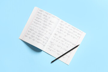 Copybook with handwritten maths formulas and pencil on blue background