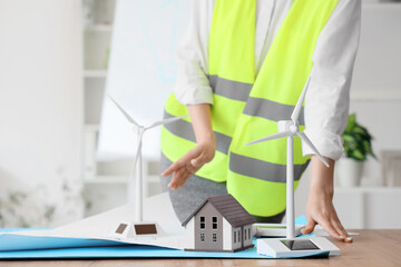 Wind turbine with house model on engineer's table in office, closeup