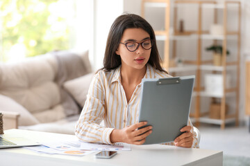 Fototapeta premium Young beautiful businesswoman working with clipboard at workplace in home office