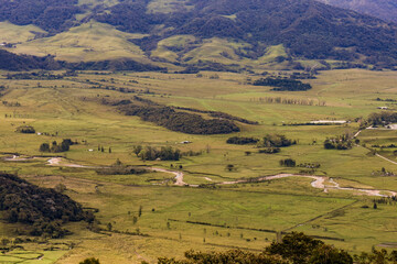 Top view of the El Valle river surrounded by farm fields and pastures, illuminated by the sunset light, in the eastern Andean mountains of central Colombia.