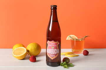 Bottle and glass of tasty kombucha tea with lemon and strawberry on white wooden table