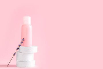 Decorative podiums with bottle of cosmetic product and lavender flowers on pink background