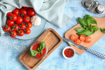 Jar of tomato sauce with basil and garlic on blue background
